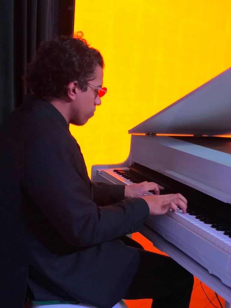 Pianista tocando piano de cauda branco em estúdio com iluminação artística