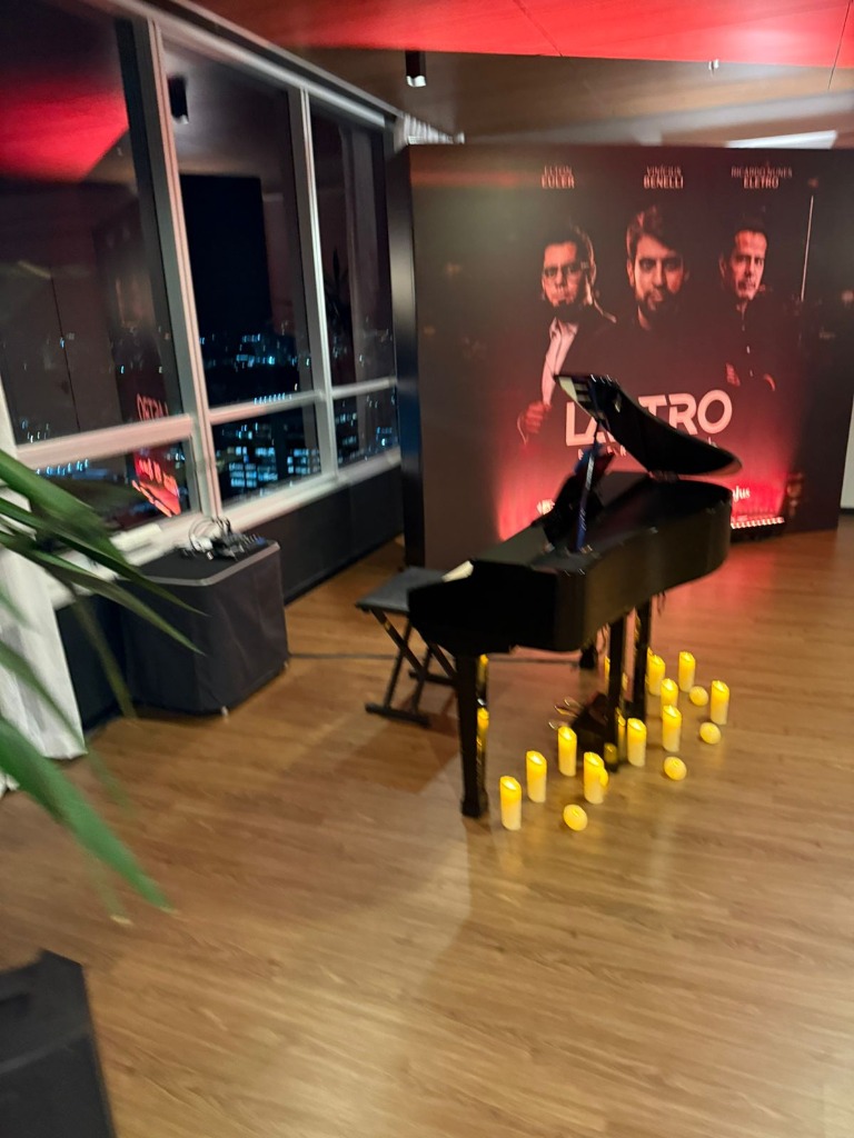 Piano de cauda preto em palco corporativo com velas