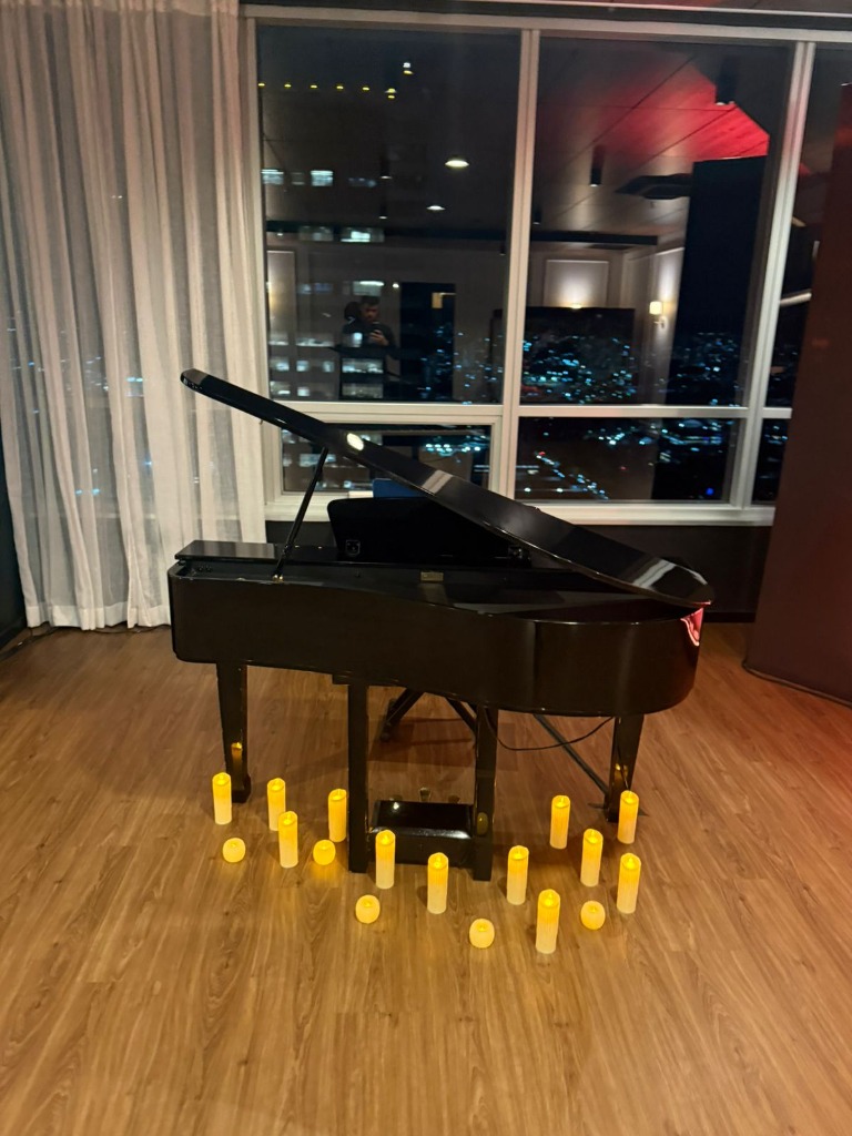 Piano de cauda preto com velas em ambiente noturno